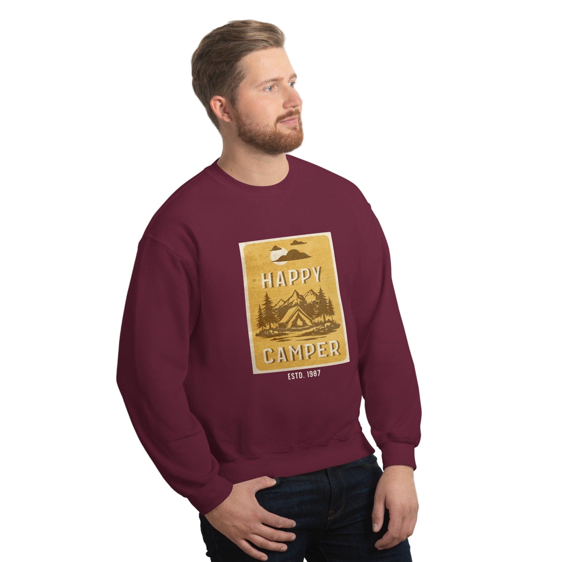 Man wearing a maroon sweatshirt with a 'Happy Camper' graphic against a white wall.
